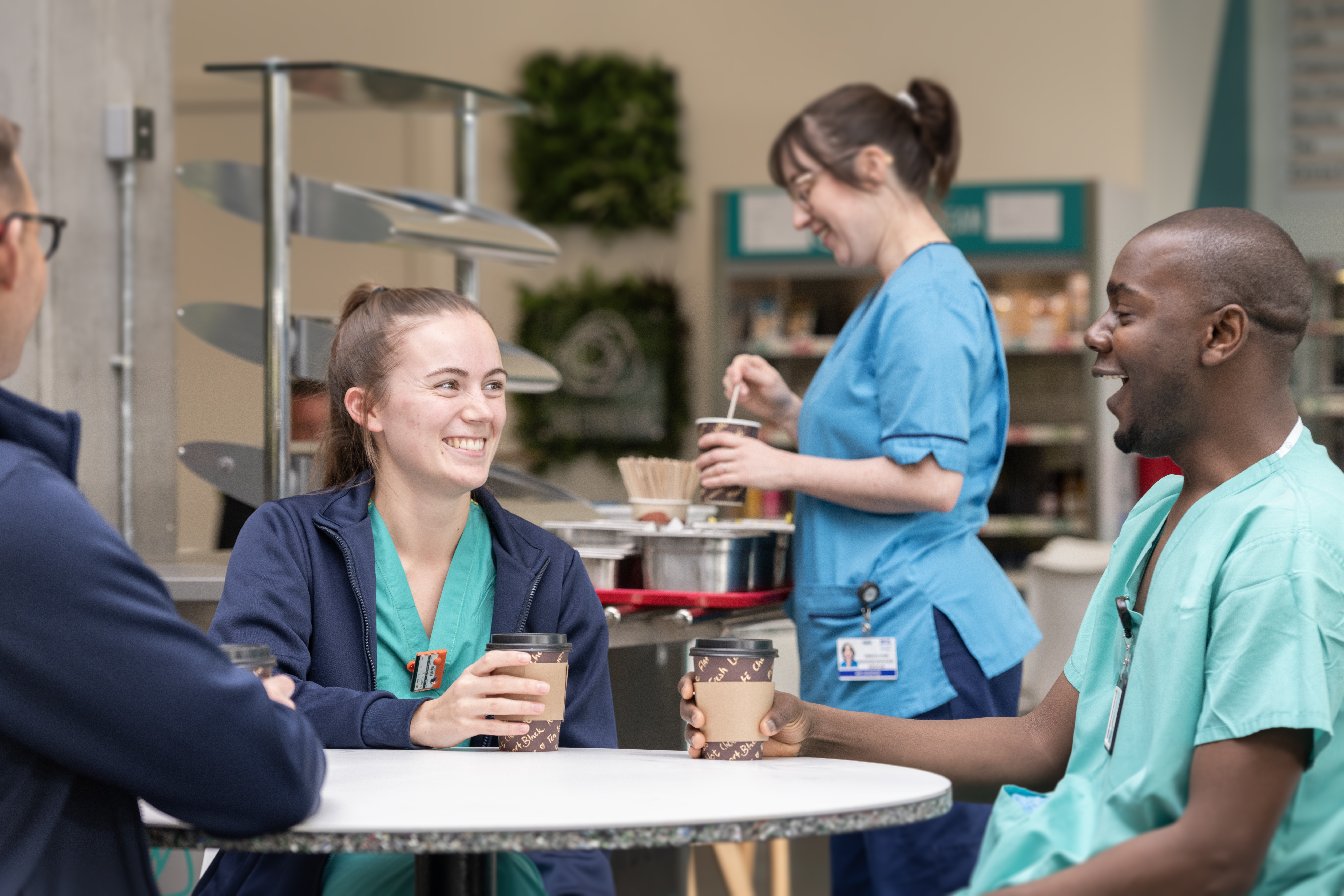 Image shows staff members conversing at a table during a rest break